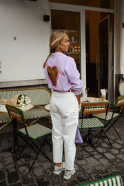 Chemise rayée à dos ouvert portée par une femme, vue de trois-quarts, ouverture en cœur dans le dos, de côté