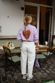 Chemise rayée à dos ouvert portée par une femme, vue de dos, ouverture en cœur dans le dos, devant un café