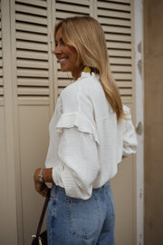 Chemise en gaze brodée portée par une femme, vue de trois-quarts, volets, regard de côté