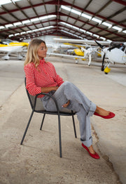 Chemise vichy col victorien portée par une femme, assise, chaise noire, escarpins rouges