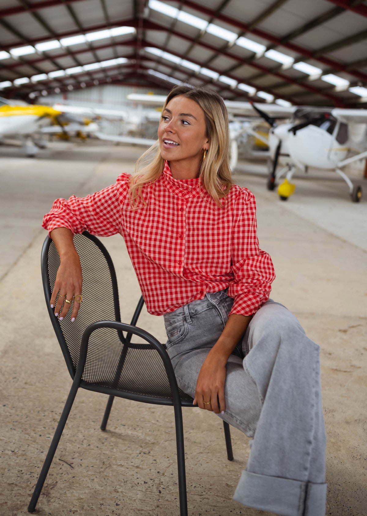 Chemise vichy col victorien portée par une femme, assise, chaise noire, hangar