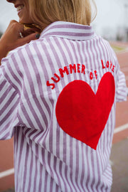 Chemise rayée à manches longues portée par une femme, vue rapprochée, cœur rouge, inscription