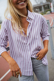 Chemise rayée à manches longues portée par une femme, vue rapprochée, rayures violettes, sourire