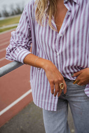 Chemise rayée à manches longues portée par une femme, vue rapprochée, rayures violettes, bague
