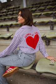 Chemise rayée à manches longues portée par une femme, assise, gradins, baskets rouges
