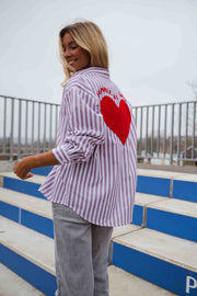 Chemise rayée à manches longues portée par une femme, vue de dos, cœur rouge, grillage