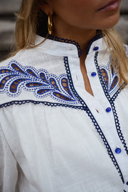 Chemise brodée à col montant portée par une femme, vue rapprochée, col montant, broderie bleue