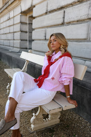 Chemise rayée à revers amovible portée par une femme, assise, sur un banc, jambes croisées