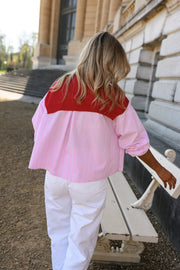 Chemise rayée à revers amovible portée par une femme, vue de dos, pull rouge sur les épaules