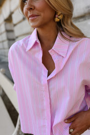 Chemise rayée à revers amovible portée par une femme, vue rapprochée, col de la chemise, boucles d'oreilles dorées