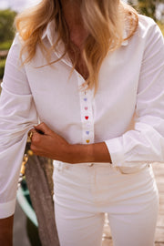 Chemise à cœurs manches longues portée par une femme, vue rapprochée, boutons colorés, ponton