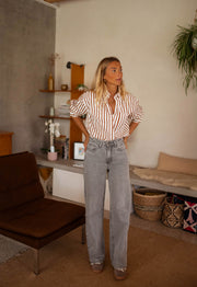 Chemise rayée boutonnée portée par une femme, silhouette entière, intérieur, étagères