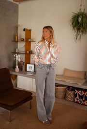 Chemise rayée boutonnée portée par une femme, vue de face, étagère, plantes