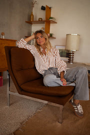 Chemise rayée boutonnée portée par une femme, assise, fauteuil, lampe