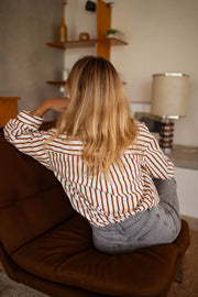 Chemise rayée boutonnée portée par une femme, vue de dos, fauteuil, cheveux blonds