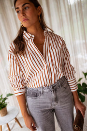 Chemise rayée boutonnée portée par une femme, vue de face, rideaux, col ouvert