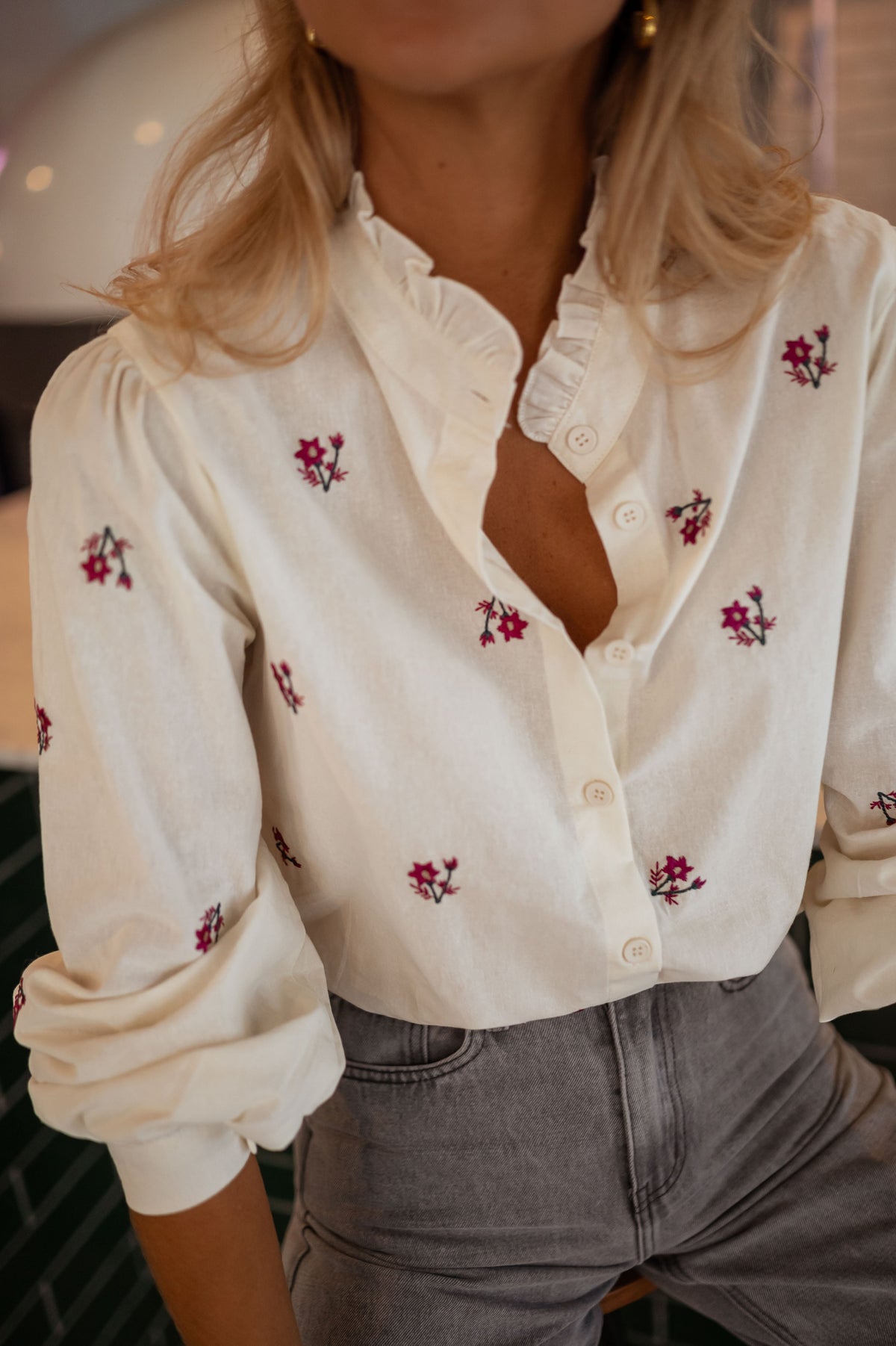 Chemise fleurie à manches longues portée par une femme, vue rapprochée, fleurs, boutons