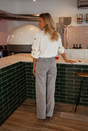 Chemise fleurie à manches longues portée par une femme, silhouette entière, comptoir, jean gris