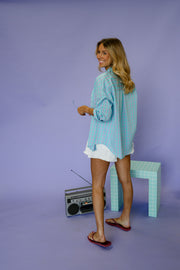 Chemise à carreaux à épaulettes turquoise portée par une femme, vue de profil, radio à côté