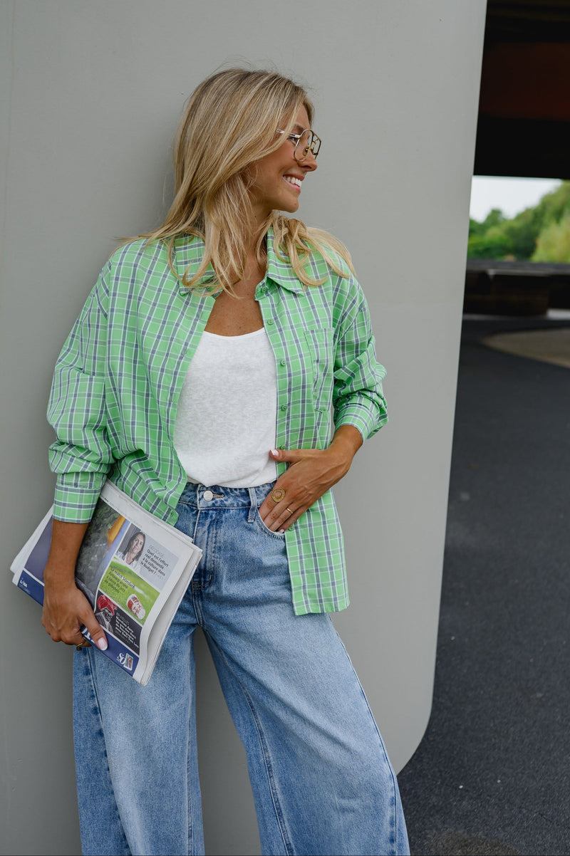 Chemise à carreaux boutonnée portée par une femme, silhouette entière, journal à la main