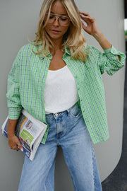 Chemise à carreaux boutonnée portée par une femme, vue rapprochée, journal à la main