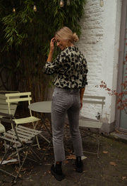 Chemise léopard légèrement ample portée par une femme, vue de dos, chaises, jardin