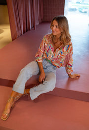 Chemise fluide manches trois-quarts portée par une femme, assise, au sol, sandales, jean clair
