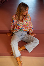 Chemise fluide manches trois-quarts portée par une femme, assise, au sol, jean clair