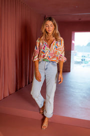 Chemise fluide manches trois-quarts portée par une femme, silhouette entière, jean clair, rideau rose