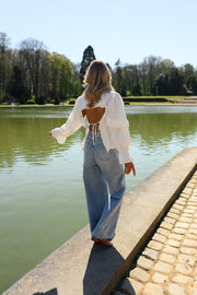 Chemise à dos ouvert volanté portée par une femme, vue de dos, berge pavée, dos ouvert