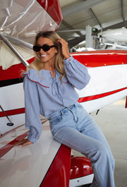 Chemise vichy col claudine portée par une femme, assise, avion rouge, lunettes de soleil