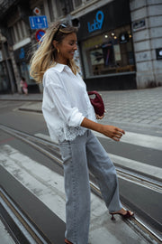 Chemise courte à dentelle portée par une femme, vue de trois-quarts, rue, sac bordeaux
