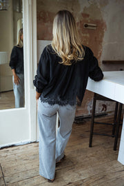 Chemise à dentelle transparente portée par une femme, vue de dos, comptoir blanc, cheveux blonds