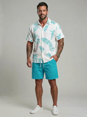 Ensemble chemise motif feuillage — feuilles turquoise et short turquoise, main dans la poche