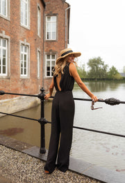 Combinaison fluide dos ouvert portée par une femme, vue de dos, chapeau, rambarde noire