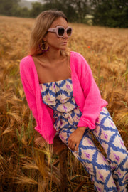 Combinaison bustier à pantalon long portée par une femme, assise, gilet rose fuchsia