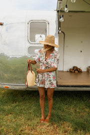Combishort fleuri manches courtes porté par une femme, silhouette entière, camping-car, porte ouverte