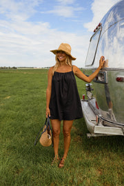 Combishort effet lin dos ouvert porté par une femme, silhouette entière, camping-car, chapeau, plan large