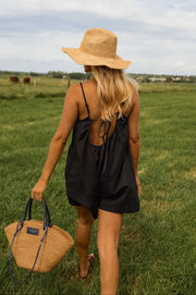 Combishort effet lin dos ouvert porté par une femme, vue de dos, chapeau de paille, panier, champ