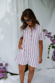 Combishort rayé à boutons porté par une femme, silhouette entière, fleurs violettes, lunettes