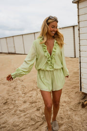 Combishort à volants boutonné porté par une femme, silhouette entière, sable, cabine de plage