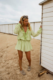 Combishort à volants boutonné porté par une femme, silhouette entière, cabine de plage, sandales