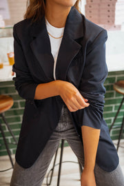 Blazer long doublé ample bleu porté par une femme, vue rapprochée, manche retroussée, jean gris