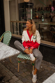 Gilet torsadé à poches porté par une femme, assise, chaise rayée, café