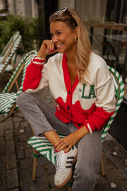 Gilet torsadé à poches porté par une femme, assise, sourire, baskets