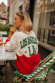 Gilet torsadé à poches porté par une femme, vue de dos, lettres LA, chaise