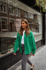 Surchemise fluide en velours verte portée par une femme, vue de face, marche, trottoir