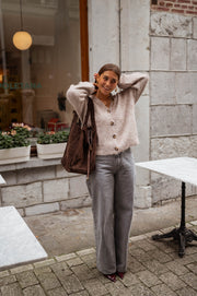 Gilet droit à col V taupe porté par une femme, vue de face, mains dans les cheveux, sac marron