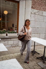 Gilet droit à col V taupe porté par une femme, silhouette entière, rue pavée, sac