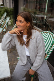 Gilet court à col rond gris porté par une femme, assise, terrasse, chaise verte